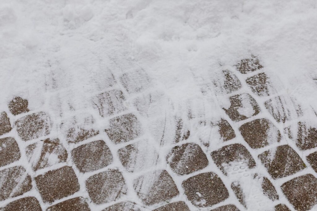 Concrete pavers partly cleared of snow, with snow still packed in the joints