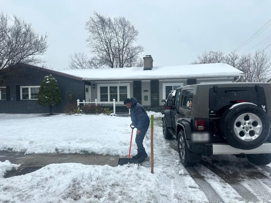 Crew member hand-shovelling beside a parked Jeep at a home in Depew, NY