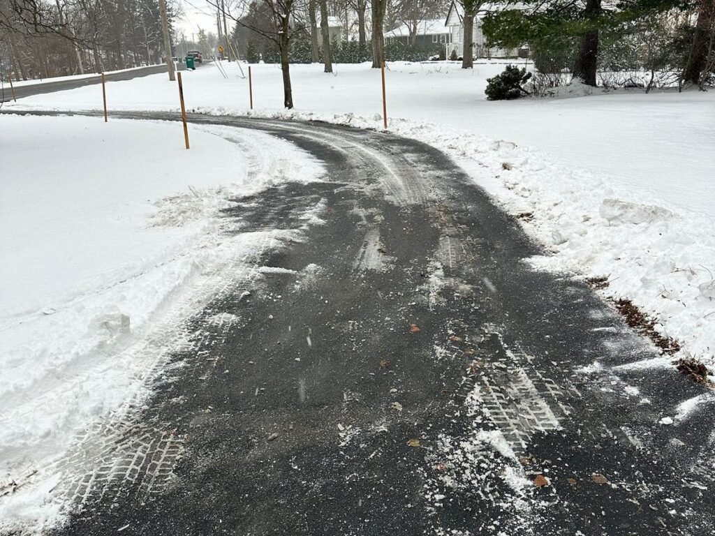 Long curved driveway plowed full width between orange marker stakes